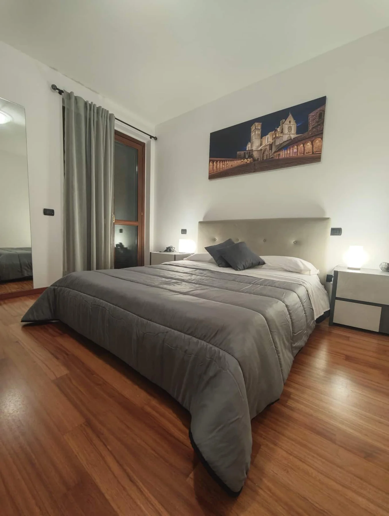 Camera matrimoniale con pavimento in legno e porta finestra